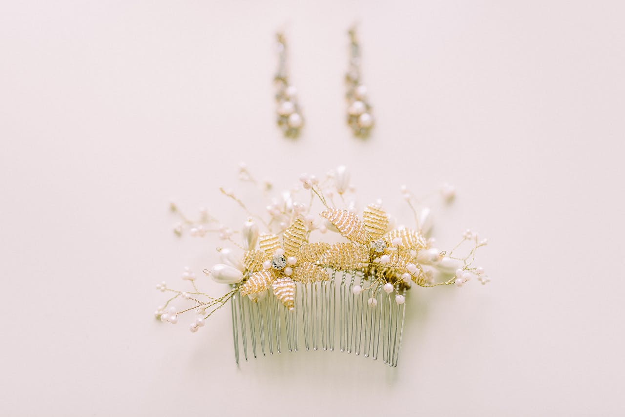 Close-up of an ornate floral hair comb with matching earrings on a soft beige background.